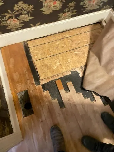 Hardwood floor repair in progress with new boards being fitted into the existing floor