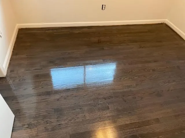 Dark stained hardwood floor in an empty room with a fresh sealed finish