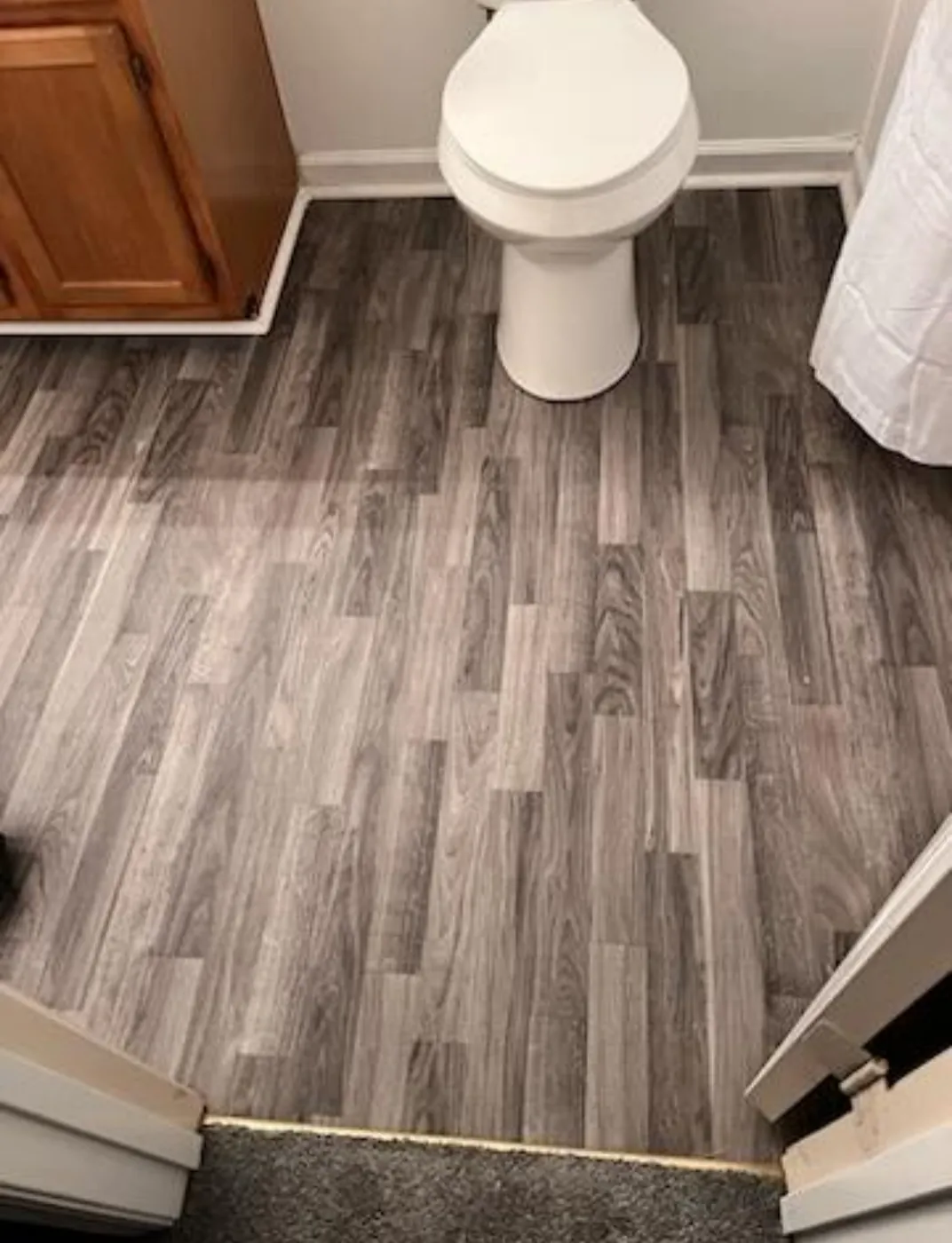 Gray wood look plank flooring in a bathroom beside the vanity and toilet