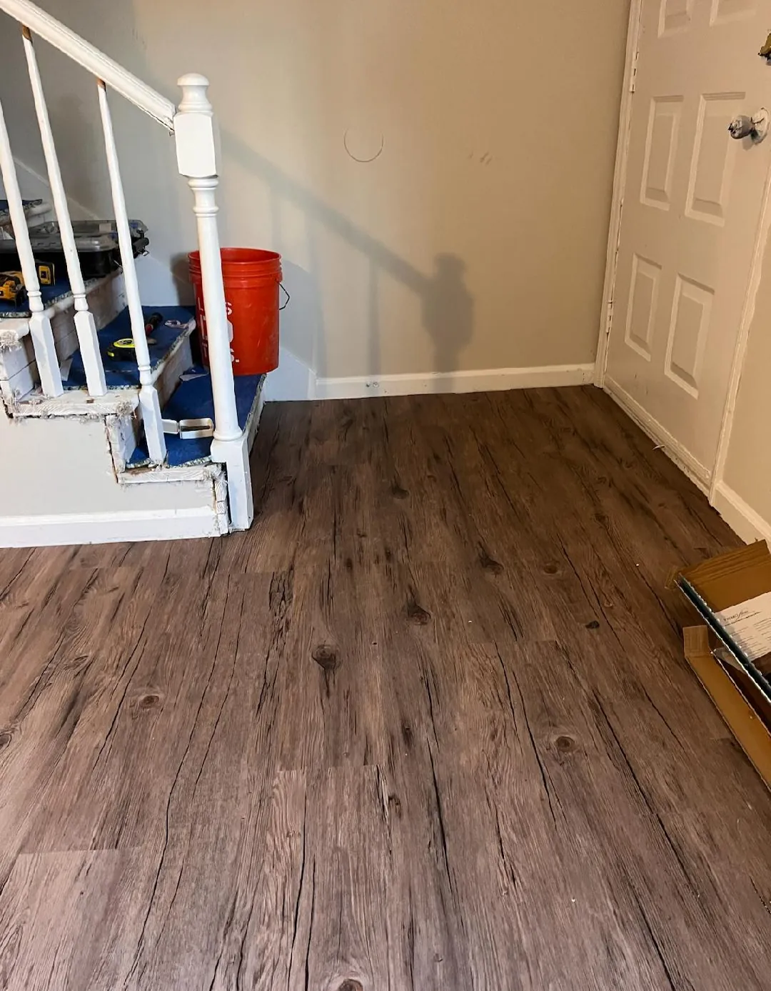 Wood look vinyl plank flooring laid in a room beside a white staircase
