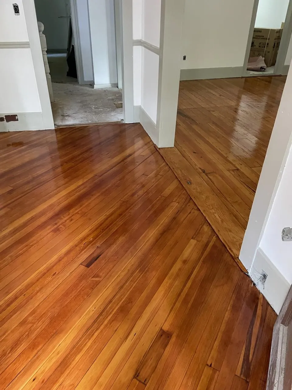 Refinished red oak hardwood floor glowing through a white doorway